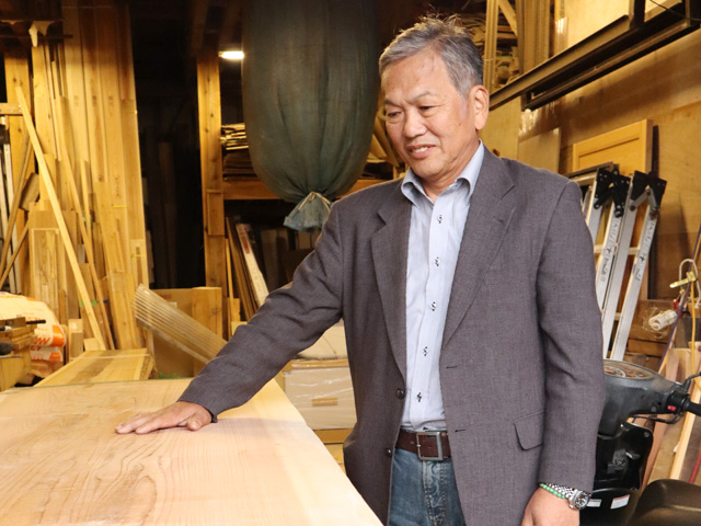 長谷川社長が木の板を触っている様子の写真